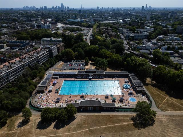 An aerial view looking towards the central London skyline, shows swimmers using Parliament Hill Fields Lido, on August 11, 2026, following weeks of hot, dry weather, with nearly three quarters of England being classified as in drought. Some 71.3 percent of England is in drought, the UK government said Monday, after the nation experienced its driest July on record, with a fifth heatwave and scant rain forecast for the week ahead. (Photo by HENRY NICHOLLS / AFP)