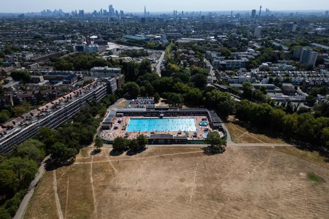 An aerial view looking towards the central London skyline, shows swimmers using Parliament Hill Fields Lido, on August 11, 2026, following weeks of hot, dry weather, with nearly three quarters of England being classified as in drought. Some 71.3 percent of England is in drought, the UK government said Monday, after the nation experienced its driest July on record, with a fifth heatwave and scant rain forecast for the week ahead. (Photo by HENRY NICHOLLS / AFP)