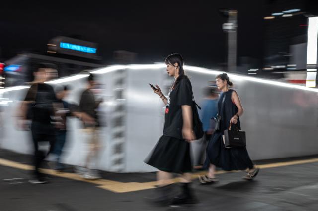 Pedestrians walk along a street in Shinjuku district in Tokyo on August 11, 2026. (Photo by Philip FONG / AFP)
