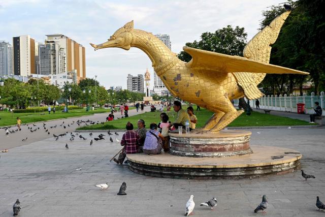 Women sit under a phoenix statue at Wat Botum park in Phnom Penh on August 11, 2026.  (Photo by TANG CHHIN Sothy / AFP)