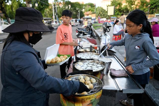 Vendor prepare coconut rice pancakes for customers at Wat Botum park in Phnom Penh on August 11, 2026.  (Photo by TANG CHHIN Sothy / AFP)