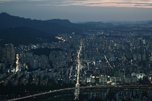 Traffic flows through streets, as seen from the Lotte World Tower, at dusk in Seoul on August 11, 2026. (Photo by GREG BAKER / AFP)