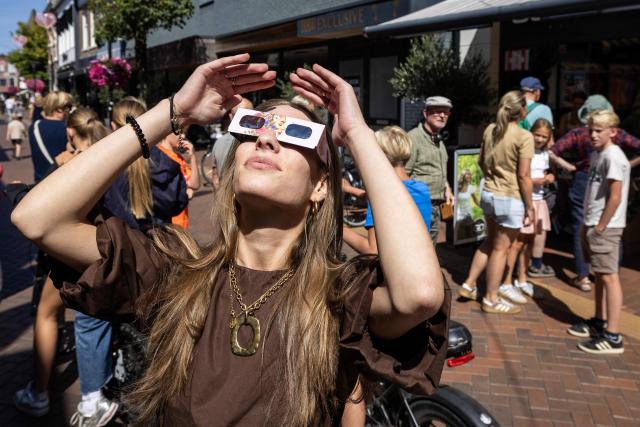 A woman wears eclipse glasses in Almelo, eastern Netherlands on August 11, 2026 on the eve of a partial solar eclipse. The scramble for protective glasses has reached fever pitch across Europe ahead of August 12, 2026 rare total solar eclipse, as pharmacies, opticians and other shops struggled to keep them in stock. (Photo by Vincent Jannink / ANP / AFP) / Netherlands OUT