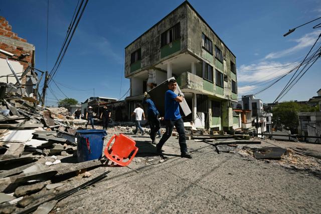 A man carrying furniture walks past a collapsed building following an earthquake in Pereira, Colombia on August 11, 2026. Colombian volunteers and rescuers cleared rubble with their bare hands to search for survivors early on August 11 after the country's strongest earthquake in a decade killed at least 169 people and smashed dozens of buildings. (Photo by Luis ACOSTA / AFP)
