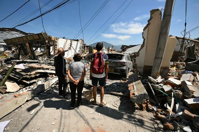 People look at a collapsed house following an earthquake in Pereira, Colombia on August 11, 2026. Colombian volunteers and rescuers cleared rubble with their bare hands to search for survivors early on August 11 after the country's strongest earthquake in a decade killed at least 169 people and smashed dozens of buildings. (Photo by Luis ACOSTA / AFP)