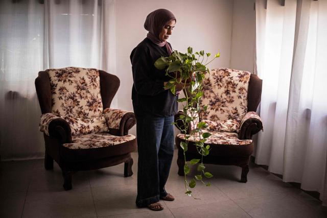 Palestinian woman Hanen Shaalan, mother of fifteen-year-old Adam, who was shot and killed outside a bakery by Israeli forces whilst getting bread, stands for a portrait while holding a pot plant that her son gifted on mother's day in Al-Duheishe Refugee Camp, south of Bethlehem, in the occupied West Bank, on August 3, 2026. B'Tselem, an Israeli rights group, reported 235 underage deaths at the hands of Israeli forces in the West Bank in the Palestinian territory since October 7, 2023, when Hamas launched a massive attack on Israel from the Gaza Strip, through June 2026, including five killed by Israeli settlers. The Palestinian Wall and Resistance Commission, a Palestinian government institution, reported 250 such deaths over the same time period. (Photo by JOHN WESSELS / AFP) / To go with 'Palestinian-Israel-Conflict-WestBank', REPORTAGE