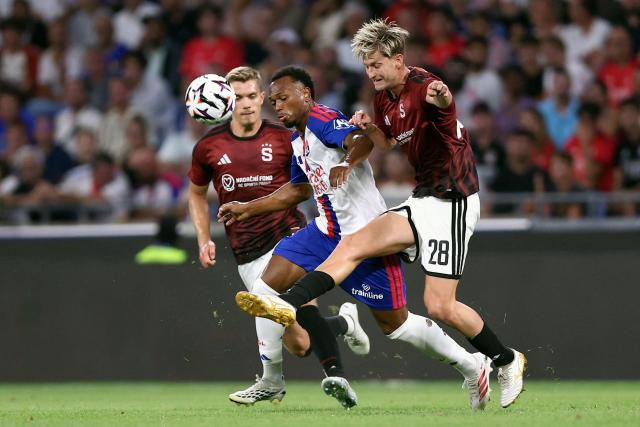 Lyon’s Belgian forward #17 LoПs Openda (C) fights for the ball with Sparta Praha's Czech midfielder #28 Roman Macek (R) during the UEFA Champions League third qualifying round - second leg football match between Olympique Lyonnais (OL) and Sparta Prague at Groupama Stadium in Decines-Charpieu, central-eastern France on August 11, 2026. (Photo by Alex MARTIN / AFP)