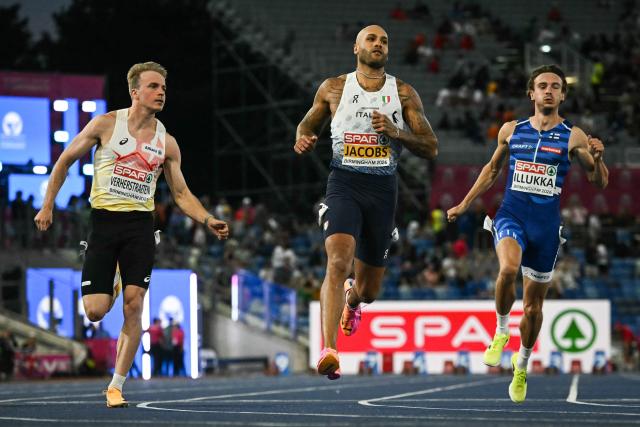 Italy's Lamont Marcell Jacobs (C) crosses the finish line to arrive first past Belgium's Simon Verherstraeten (L) and Finland's Riku Illukka (R) in the men's 100m semi-final during the European Athletics Championships at Alexander Stadium in Birmingham on August 11, 2026. (Photo by Paul ELLIS / AFP)