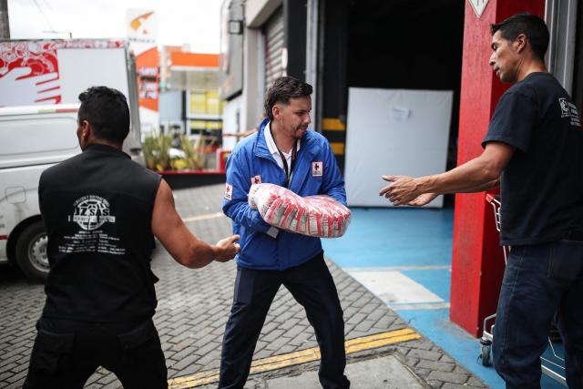 People and a Colombian Red Cross member gather aid for earthquake victims in Bogota on August 11, 2026. Colombian volunteers and rescuers cleared rubble with their bare hands to search for survivors early on August 11 after the country's strongest earthquake in a decade killed at least 169 people and smashed dozens of buildings. (Photo by ESTEBAN VEGA LA-ROTTA / AFP)