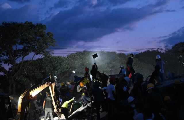 Rescuers and volunteers search for survivors amid the rubble of a collapsed building after an earthquake in Cali, Colombia on August 11, 2026. Colombian volunteers and rescuers cleared rubble with their bare hands to search for survivors early on August 11 after the country's strongest earthquake in a decade killed at least 169 people and smashed dozens of buildings. (Photo by Joaquin SARMIENTO / AFP)