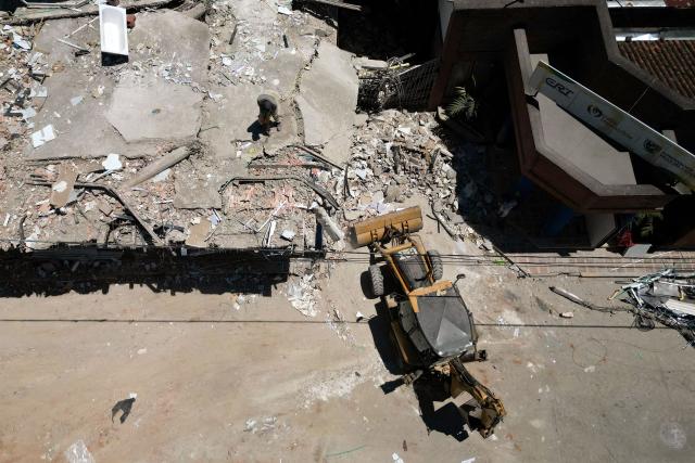 Aerial view shows a man working on a destroyed house after an earthquake in Zarzal, Valle del Cauca, Colombia on August 11, 2026. Rescuers, soldiers and volunteers searched through collapsed apartment blocks and office buildings across western Colombia, racing to find survivors after the country's strongest earthquake in a century killed at least 241 people and left many more homeless. (Photo by Raul ARBOLEDA / AFP)