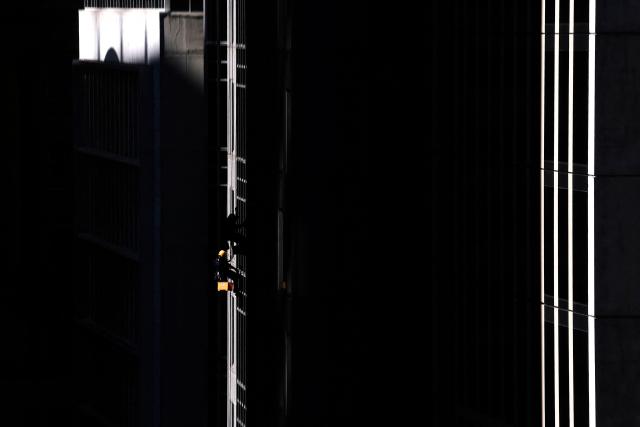 Window cleaners hang from ropes as they descend the front of a building in the central business district (CBD) of Sydney on August 12, 2026. (Photo by DAVID GRAY / AFP)