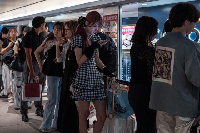 People line up at a souvenir shop in Tokyo station on August 12, 2026. (Photo by Philip FONG / AFP)