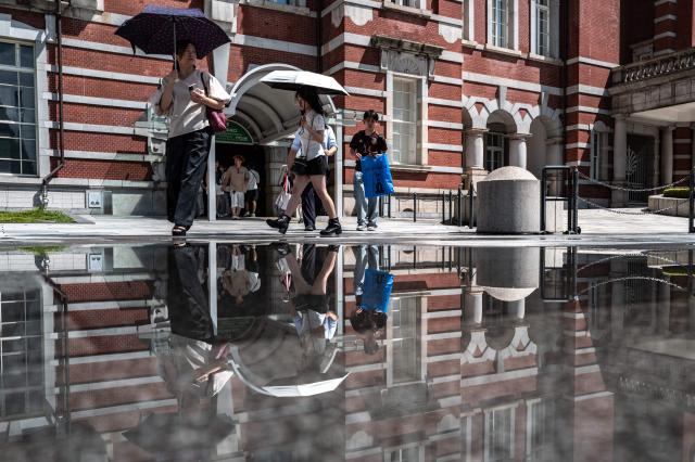 People walk outside the Tokyo station on August 12, 2026. (Photo by Philip FONG / AFP)