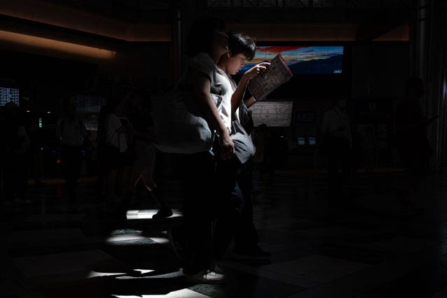 Commuters walk in Tokyo station on August 12, 2026. (Photo by Philip FONG / AFP)