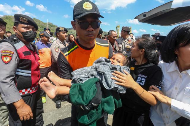 A rescue worker carries an evacuated child at Lembar port in West Lombok on August 12, 2026. A navy vessel and other ships rushed in on August 12 to rescue over 100 people from a ferry on fire off the Indonesian tourist island of Bali, officials said, in the second such incident in days. (Photo by AFP)