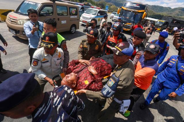 TOPSHOT - Rescue workers and local authorities carry an elderly passenger on a stretcher towards waiting ambulances at Lembar port in West Lombok on August 12, 2026. A navy vessel and other ships rushed in on August 12 to rescue over 100 people from a ferry on fire off the Indonesian tourist island of Bali, officials said, in the second such incident in days. (Photo by AFP)