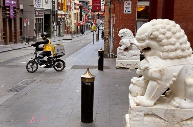 (FILES) A food delivery rider rides down a street in Melbourne's Chinatown on October 19, 2021. Hundreds of thousands of gig workers in Australia have been granted a huge pay rise from August 17, 2026 under a decision by the country's workplace relations tribunal lauded as "world-leading". (Photo by William WEST / AFP)