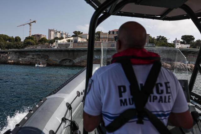 A member of French municipal police marine unit patrols off the Corniche to monitor for people diving from the coastline, in Marseille, on July 31, 2026. Suspended between sea and sky and stretching for three kilometers, the Corniche Kennedy offers a unique city-center setting for daredevil teens. Young divers brave both danger and the authorities leaping into the translucent water - just as they do every summer - while social media attracts new enthusiasts among visiting tourists. (Photo by Thibaud MORITZ / AFP)