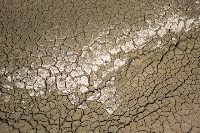 This aerial photograph shows the parched bed of Brenets Lake (Lac des Brenets), part of the Doubs River, a natural border between eastern France and western Switzerland, as central Europe is hit by a new heatwave, in Les Brenets on August 11, 2026. The river has dried up due to a combination of factors, including geological fissures that drain water underground, below-average rainfall and repeated heatwaves. (Photo by Fabrice COFFRINI / AFP)