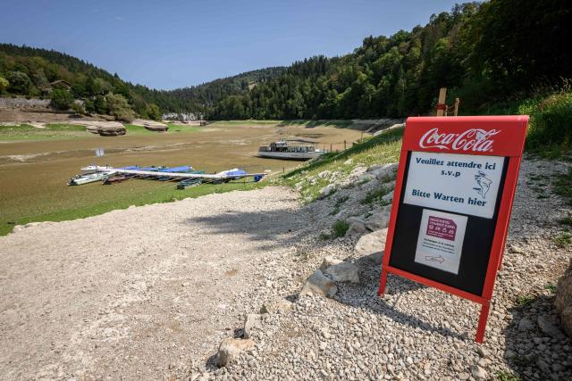 This photograph shows the parched bed of Brenets Lake (Lac des Brenets), part of the Doubs River, a natural border between eastern France and western Switzerland, as central Europe is hit by a new heatwave, in Les Brenets on August 11, 2026. The river has dried up due to a combination of factors, including geological fissures that drain water underground, below-average rainfall and repeated heatwaves. (Photo by Fabrice COFFRINI / AFP)