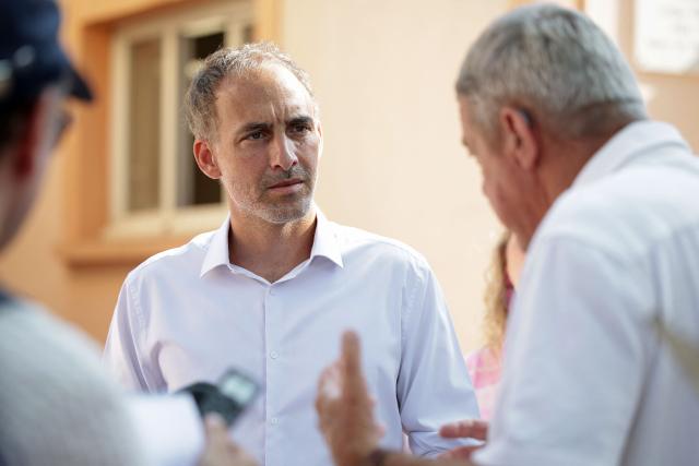 French politician, centre-left party Place publique's leader and MEP Raphael Glucksmann (L) speaks with the mayor of Jonquieres Jacques Piraud (R), as he meets with the residents affected by last year's wildfire, in Jonquiere, south-western France, on August 12, 2026. (Photo by Valentine CHAPUIS / AFP)