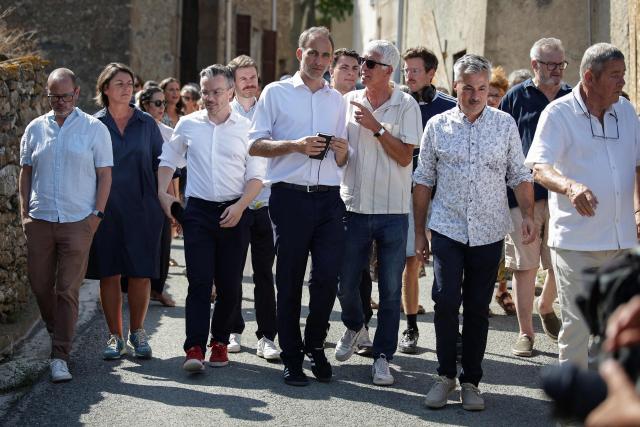 Co-president of French center-left party Place publique (PP) Raphael Glucksmann (C) walks as he meets with the residents affected by last year's wildfire, in Jonquiere, south-western France, on August 12, 2026. glu (Photo by Valentine CHAPUIS / AFP)