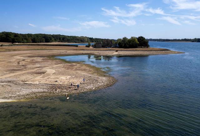 An aerial view of Anglian Water's Rutland Water reservoir shows the remains of buildings in the former hamlet of Middle Hambleton, revealed in the bed of the reservoir by the receding water -- a reservoir created by the flooding of hamlets Lower and Middle Hambleton -- due to the persistent hot weather and drought, in Upper Hambleton, central England on August 12, 2026. England and Wales experienced their driest July on record this year, with high temperatures and low rainfall across swathes of the country having plunged almost three-quarters of England and all of Wales into drought. (Photo by HENRY NICHOLLS / AFP)