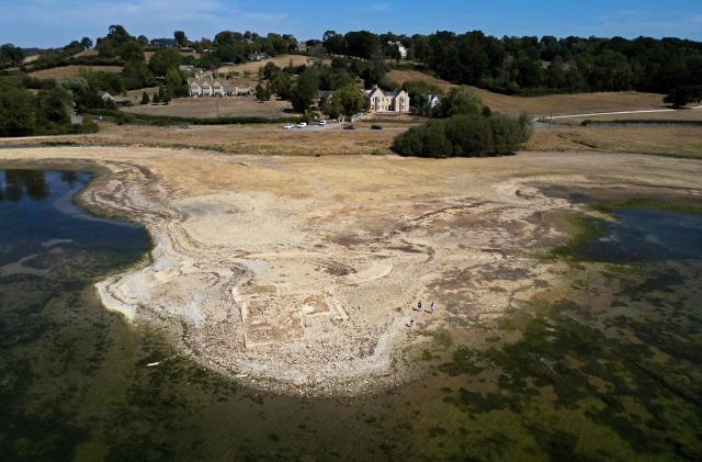 An aerial view of Anglian Water's Rutland Water reservoir shows the remains of buildings in the former hamlet of Middle Hambleton, revealed in the bed of the reservoir by the receding water -- a reservoir created by the flooding of hamlets Lower and Middle Hambleton -- due to the persistent hot weather and drought, in Upper Hambleton, central England on August 12, 2026. England and Wales experienced their driest July on record this year, with high temperatures and low rainfall across swathes of the country having plunged almost three-quarters of England and all of Wales into drought. (Photo by HENRY NICHOLLS / AFP)
