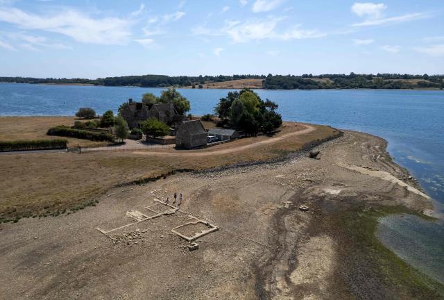 An aerial view of Anglian Water's Rutland Water reservoir shows the remains of buildings in the former hamlet of Middle Hambleton, revealed in the bed of the reservoir by the receding water -- a reservoir created by the flooding of hamlets Lower and Middle Hambleton -- due to the persistent hot weather and drought, in Upper Hambleton, central England on August 12, 2026. England and Wales experienced their driest July on record this year, with high temperatures and low rainfall across swathes of the country having plunged almost three-quarters of England and all of Wales into drought. (Photo by HENRY NICHOLLS / AFP)