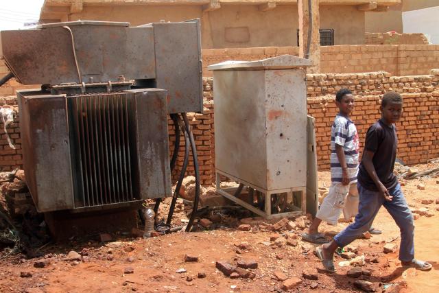 Boys walk past an electricity transformer that was hit by a drone strike in the El-Droshab area of Khartoum North, on August 12, 2026. Sudan's paramilitary Rapid Support Forces launched drone strikes on capital Khartoum and other army-controlled cities on August 12, in what appeared to be their largest coordinated attack in months. (Photo by Ebrahim Hamid / AFP)