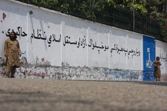 Taliban security personnel stand guard next to a wall mural depicted along a street in Jalalabad on August 12, 2026 ahead of the fifth anniversary of their takeover of Afghanistan. (Photo by Aimal Zahir / AFP)