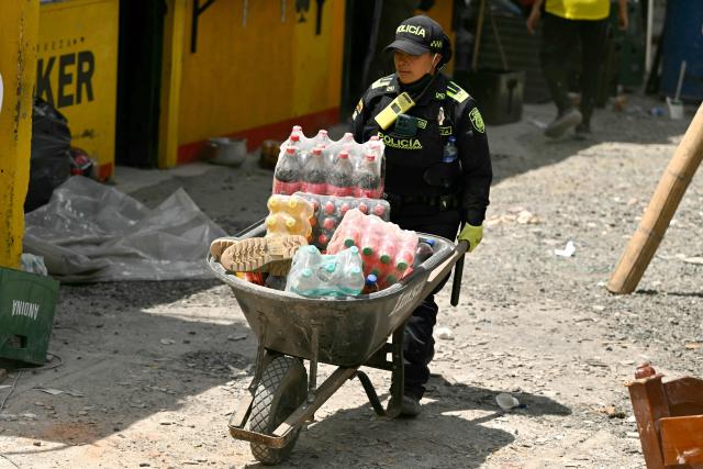 A Colombian Police officer carries aid for earthquake victims in Pereira, Colombia on August 12, 2026. Rescuers, soldiers and volunteers searched through collapsed apartment blocks and office buildings across western Colombia, racing to find survivors after the country's strongest earthquake in a century killed at least 239 people and left many more homeless on August 10, 2026. The 7.4-magnitude quake injured more than 1,670 people, according to a tally by municipal authorities. (Photo by Luis ACOSTA / AFP)