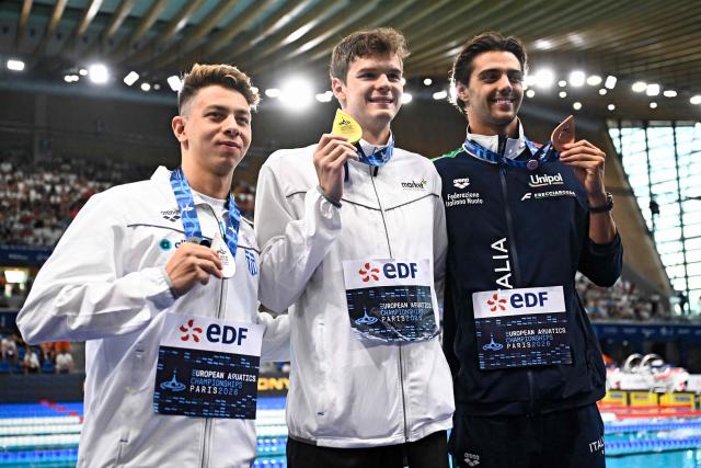 (LtoR) Greece's Apostolos Siskos (silver medal), Hungary's Hubert Kos (gold medal) and Italy's Thomas Ceccon (bronze medal) pose on the podium of the men's 200m backstroke swimming event during the LEN European Aquatics Championships at the Olympic Aquatic Centre in Saint-Denis, northern suburbs of Paris, on August 12, 2026. (Photo by JULIEN DE ROSA / AFP)