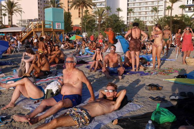 People observe the total solar eclipse from the Arenal beach in Llucmajor, on the Balearic island of Mallorca, on August 12, 2026. Millions of Europeans will contemplate the sky in awe today during a rare total solar eclipse that will plunge a swathe of Spain into an eerie daytime darkness. The shadow cast when the Moon covers the Sun will begin in Russia's remote Arctic north at around 1700 GMT and will continue in an arc through Greenland and Iceland. Spain is where most people will view the total eclipse, which will cross the country diagonally from the northern Atlantic coast to the Mediterranean Sea, where it will vanish at around 1830 GMT. (Photo by Jaime REINA / AFP)