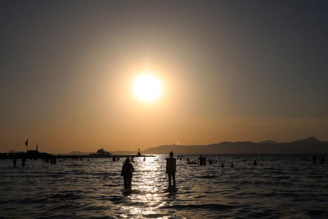 TOPSHOT - People observe the total solar eclipse from the Arenal beach in Llucmajor, on the Balearic island of Mallorca, on August 12, 2026. Millions of Europeans will contemplate the sky in awe today during a rare total solar eclipse that will plunge a swathe of Spain into an eerie daytime darkness. The shadow cast when the Moon covers the Sun will begin in Russia's remote Arctic north at around 1700 GMT and will continue in an arc through Greenland and Iceland. Spain is where most people will view the total eclipse, which will cross the country diagonally from the northern Atlantic coast to the Mediterranean Sea, where it will vanish at around 1830 GMT. (Photo by Jaime REINA / AFP)