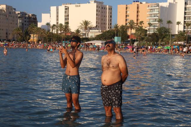 People observe the total solar eclipse from the Arenal beach in Llucmajor, on the Balearic island of Mallorca, on August 12, 2026. Millions of Europeans will contemplate the sky in awe today during a rare total solar eclipse that will plunge a swathe of Spain into an eerie daytime darkness. The shadow cast when the Moon covers the Sun will begin in Russia's remote Arctic north at around 1700 GMT and will continue in an arc through Greenland and Iceland. Spain is where most people will view the total eclipse, which will cross the country diagonally from the northern Atlantic coast to the Mediterranean Sea, where it will vanish at around 1830 GMT. (Photo by Jaime REINA / AFP)