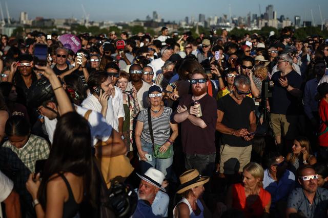 People use special protective glasses as they watch a near total solar eclipse, with more than 90 percent of the Sun blocked by the Moon across Britain, from Primrose Hill in London on August 12, 2026. Millions of people will turn their gaze towards the heavens on August 12 to witness one of nature's greatest spectacles -- a rare total solar eclipse -- as it sweeps over mainland Europe to briefly turn day into night. (Photo by Henry NICHOLLS / AFP)