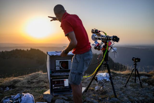 An astronomy enthusiast observes a partial solar eclipse at the Chasseral peak, above Nods, northwestern Switzerland, on August 12, 2026. The eclipse was mainland Europe's first total eclipse since 2006. Throughout human history eclipses have stirred amazement, fear and reverence, as they appear to momentarily halt the normal course of nature, creating a strange twilight during which temperatures drop, shadows appear at strange angles and some animals go to sleep. (Photo by Fabrice COFFRINI / AFP)