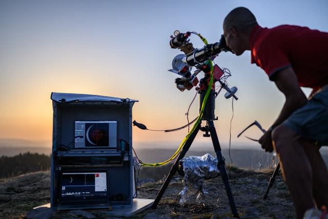 An astronomy enthusiast observes a partial solar eclipse at the Chasseral peak, above Nods, northwestern Switzerland, on August 12, 2026. The eclipse was mainland Europe's first total eclipse since 2006. Throughout human history eclipses have stirred amazement, fear and reverence, as they appear to momentarily halt the normal course of nature, creating a strange twilight during which temperatures drop, shadows appear at strange angles and some animals go to sleep. (Photo by Fabrice COFFRINI / AFP)