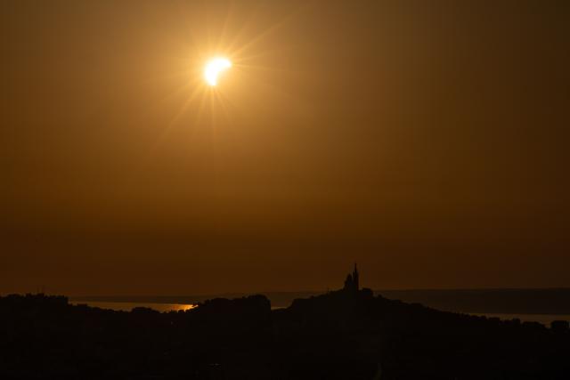 The moon passes over the sun's horizon behind the Notre-Dame de la Garde Basilica, nicknamed the “Bonne Mиre,” during a partial solar eclipse in Marseille, in southeastern France, on August 12, 2026. In France, the solar eclipse was not total - after the total solar eclipse of 1999 France will not see another total eclipse for another 55 years in 2081. (Photo by Thibaud MORITZ / AFP)