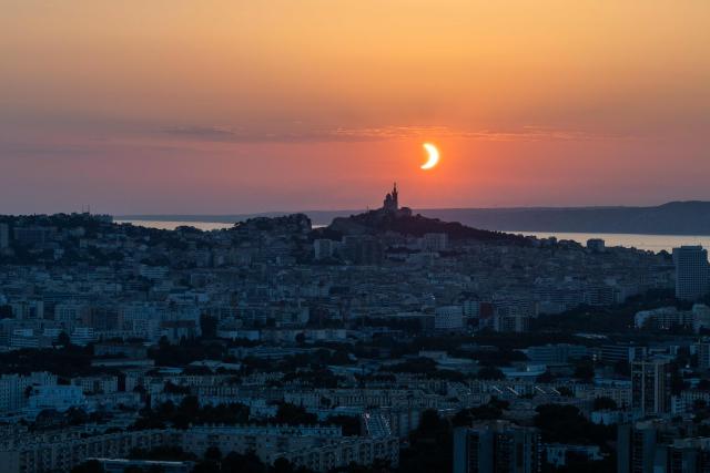 The moon passes over the sun's horizon behind the Notre-Dame de la Garde Basilica, nicknamed the “Bonne Mиre,” during a partial solar eclipse in Marseille, in southeastern France, on August 12, 2026. In France, the solar eclipse was not total - after the total solar eclipse of 1999 France will not see another total eclipse for another 55 years in 2081. (Photo by Thibaud MORITZ / AFP)