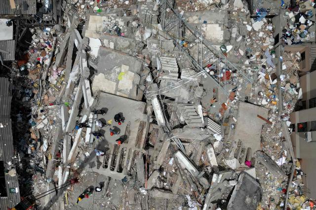 This aerial view shows rescuers searching for survivors amid the rubble of a collapsed building after an earthquake in Cali, Colombia on August 12, 2026. Colombia's government on August 12 declared three days of mourning for victims of an earthquake that demolished buildings in the west of the country, killing more than 200 people. (Photo by Raul ARBOLEDA / AFP)