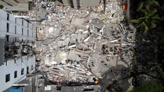 This aerial view shows rescuers searching for survivors amid the rubble of a collapsed building after an earthquake in Cali, Colombia on August 12, 2026. Colombia's government on August 12 declared three days of mourning for victims of an earthquake that demolished buildings in the west of the country, killing more than 200 people. (Photo by Raul ARBOLEDA / AFP)