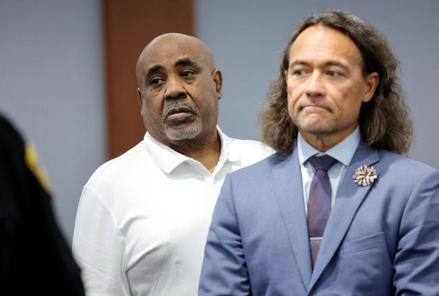 Duane Davis (L) stands with his attorney Michael Sanft as prospective jurors enter the courtroom during the third day of jury selection in his murder trial, related to the 1996 killing of rapper Tupac Shakur, at Clark County District Court Regional Justice Center in Las Vegas, Nevada, on August 12, 2026. The trial of the former gang leader accused of orchestrating the murder of rapper Tupac Shakur finally began on August 10, 30 years after one of America's most high-profile unresolved killings. The proceedings, expected to last a month, will likely not make clear who fired the shots that killed the California hip-hop legend on the night of September 7, 1996, while he was in Las Vegas to see a Mike Tyson boxing match. (Photo by Steve Marcus / POOL / AFP)