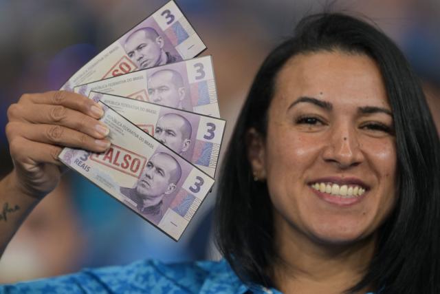 A Cruzeiro fan holds mock banknotes reading "FALSE" and bearing the image of Flamengo Portuguese head coach Leonardo Jardim, a former Cruzeiro coach, ahead of the first leg of the Copa Libertadores round of 16 football match between Brazilian teams Cruzeiro and Flamengo at the Mineirao stadium in Belo Horizonte, Minas Gerais state, Brazil, on August 12, 2026. (Photo by DOUGLAS MAGNO / AFP)