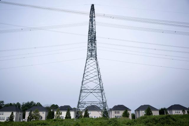 Transmission towers and power lines are shown adjacent to single-family homes with nearby data center infrastructure in Stone Ridge, Virginia on August 12, 2026. Hastily built to meet skyrocketing demand for computing power required by the global artificial intelligence race, data centers are facing opposition across the United States. (Photo by Brendan Smialowski / AFP)