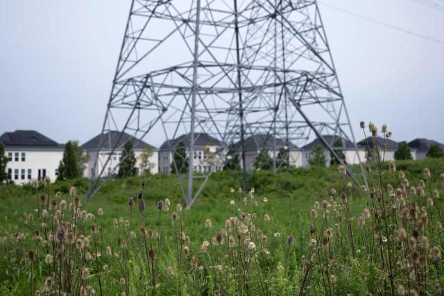 A transmission tower is shown adjacent to single-family homes with nearby data center infrastructure in Stone Ridge, Virginia on August 12, 2026. Hastily built to meet skyrocketing demand for computing power required by the global artificial intelligence race, data centers are facing opposition across the United States. (Photo by Brendan Smialowski / AFP)