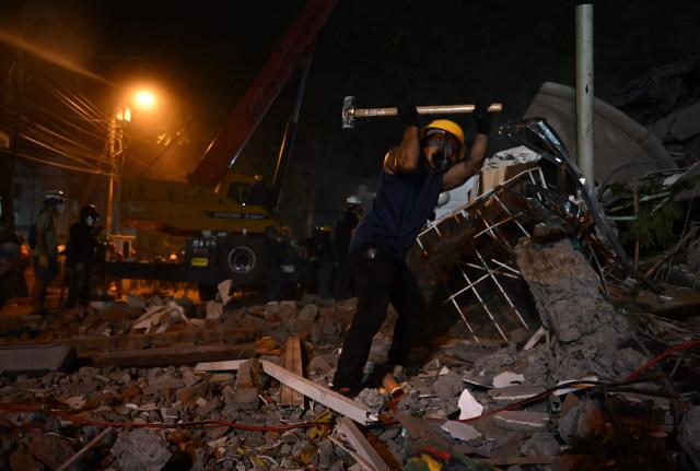 A volunteer removes rubble as they search for survivors at the site of collapsed buildings after an earthquake in Cali, Colombia on August 12, 2026. Rescuers, soldiers and volunteers searched through collapsed apartment blocks and office buildings across western Colombia, racing to find survivors after the country's strongest earthquake in a century killed at least 239 people and left many more homeless on August 10, 2026. The 7.4-magnitude quake injured more than 1,670 people, according to a tally by municipal authorities. (Photo by Raul ARBOLEDA / AFP)