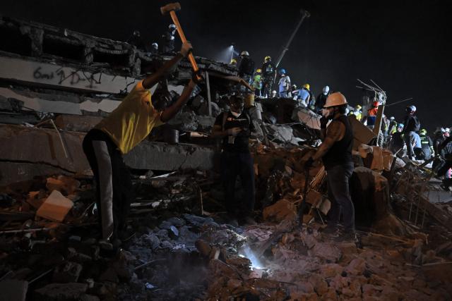 Rescue workers and volunteers remove rubble as they search for survivors at the site of collapsed buildings after an earthquake in Cali, Colombia on August 12, 2026. Rescuers, soldiers and volunteers searched through collapsed apartment blocks and office buildings across western Colombia, racing to find survivors after the country's strongest earthquake in a century killed at least 239 people and left many more homeless on August 10, 2026. The 7.4-magnitude quake injured more than 1,670 people, according to a tally by municipal authorities. (Photo by Raul ARBOLEDA / AFP)